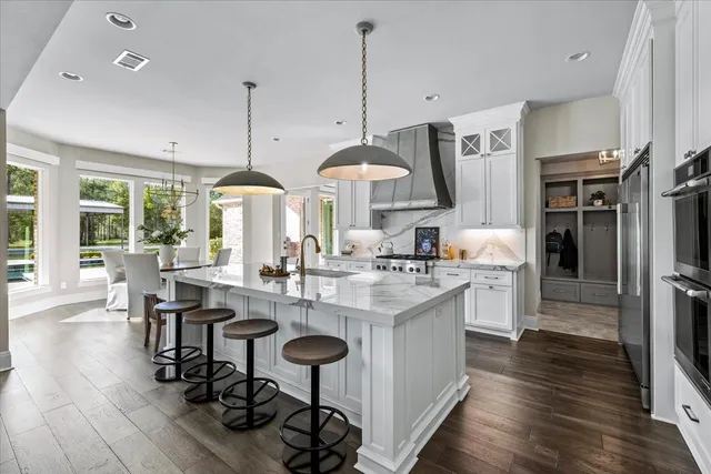 a kitchen with stainless steel appliances a dining table chairs a sink and white cabinets