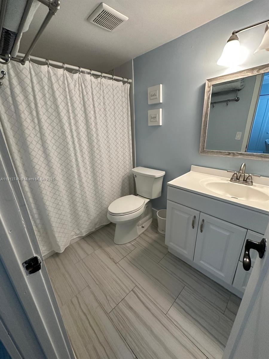 10040 Northwest 9th St Circle, Unit 202 Miami, FL 33172 - Photo 11 of 17 a bathroom with a sink a toilet a mirror and vanity