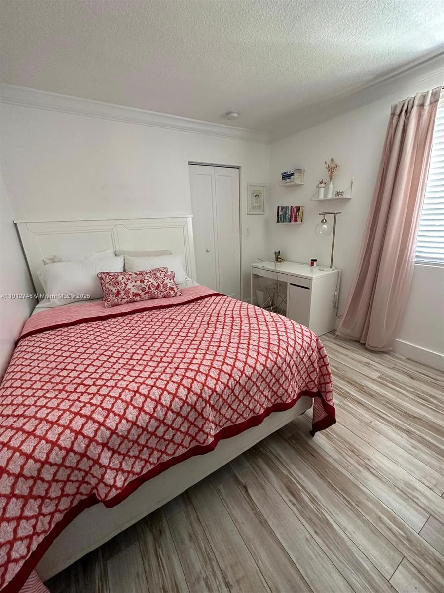 10040 Northwest 9th St Circle, Unit 202 Miami, FL 33172 - Photo 10 of 17 a bedroom with a bed and wooden floor