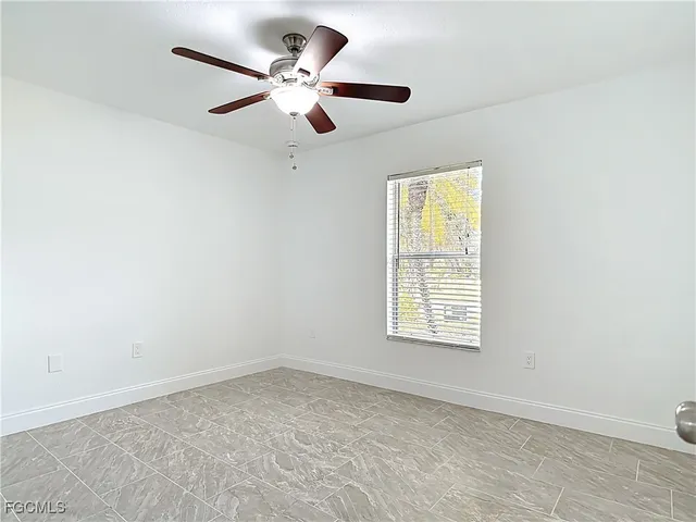 an empty room with a window and a fan