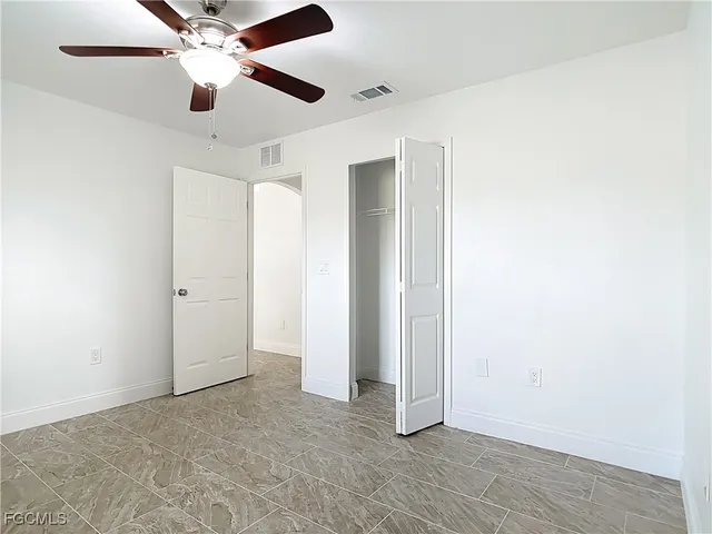 an empty room with closet and a ceiling fan