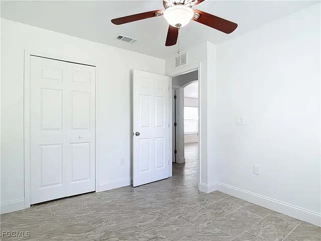 an empty room with a ceiling fan and a window