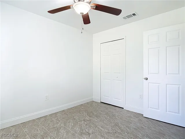 an empty room with a ceiling fan and a window