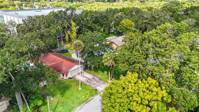 an aerial view of residential house with outdoor space and trees all around