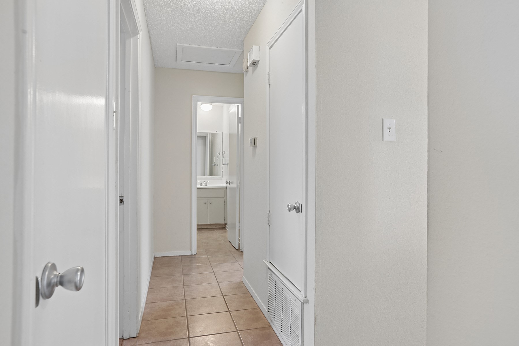 3114 Plantation Road, Unit A Austin, TX 78745 - Photo 6 of 15 A well-maintained hallway with tiled flooring leads to a bright bathroom.