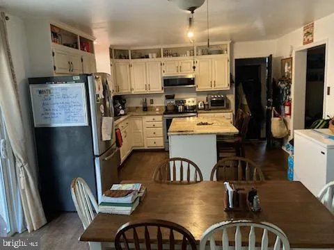 a kitchen with stainless steel appliances granite countertop a refrigerator a stove top oven a sink dishwasher and chairs