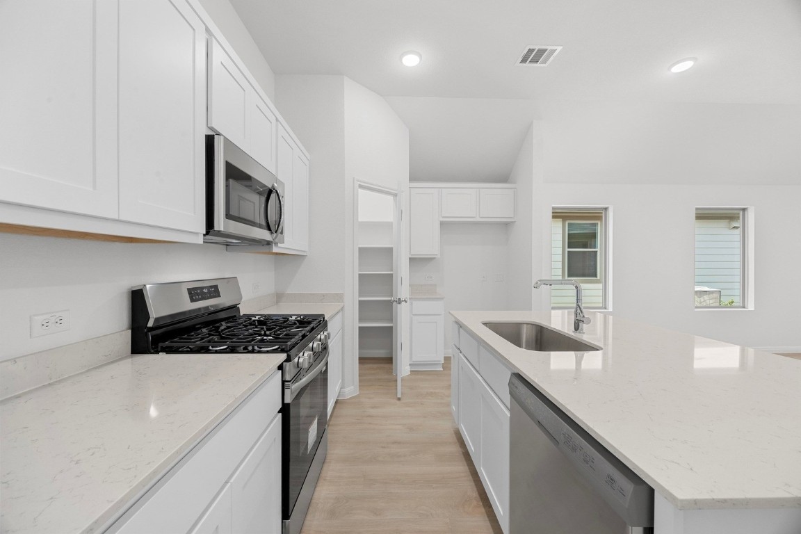 298 Bendecido Loop Elgin, TX 78621 - Photo 5 of 40 a kitchen with stainless steel appliances granite countertop a sink stove and cabinets