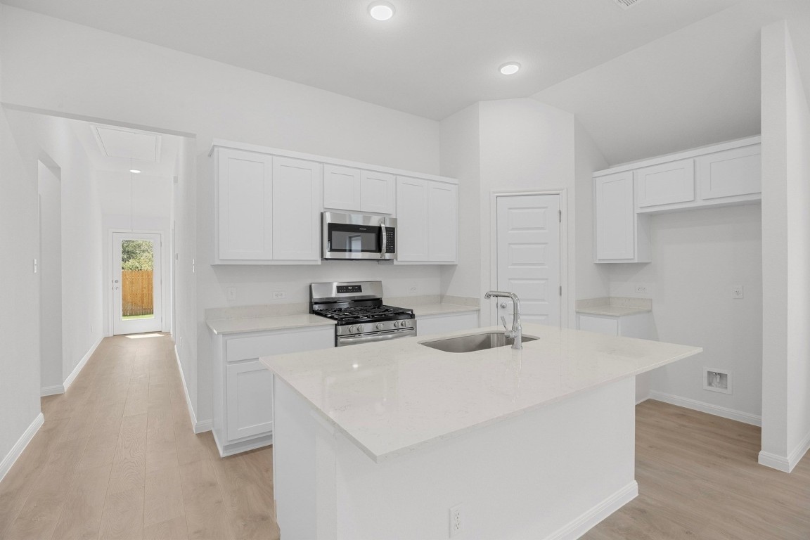 298 Bendecido Loop Elgin, TX 78621 - Photo 7 of 40 a kitchen with stainless steel appliances a sink a stove a chimney a refrigerator and cabinets
