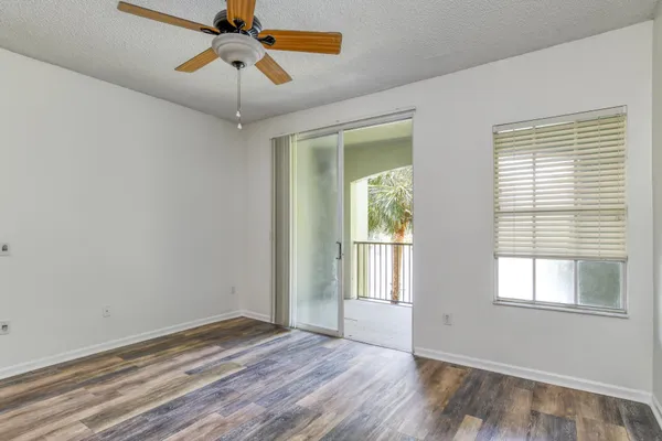 a view of empty room with wooden floor and fan