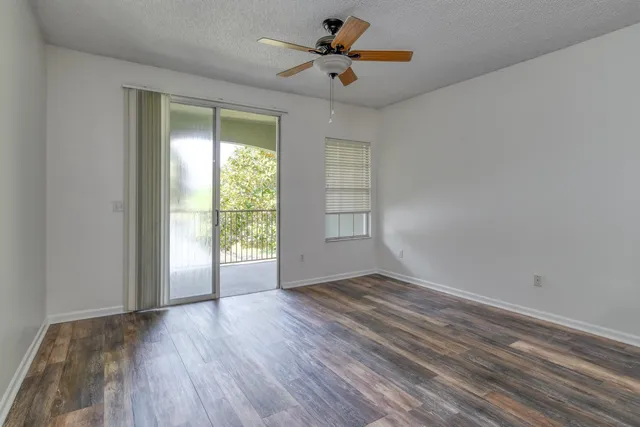 a view of an empty room with a window and wooden floor