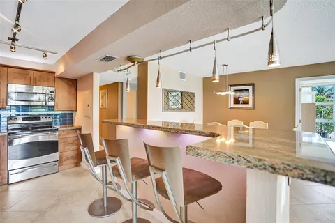 a kitchen with granite countertop kitchen island stainless steel appliances a sink and counter space