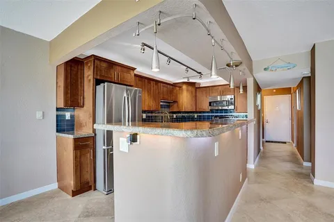 a kitchen with stainless steel appliances granite countertop a refrigerator a sink dishwasher stove and open cabinets