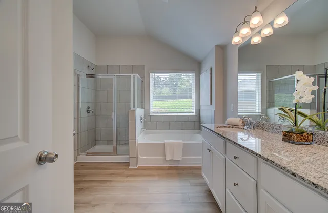 a bathroom with a granite countertop bathtub a sink and a large mirror