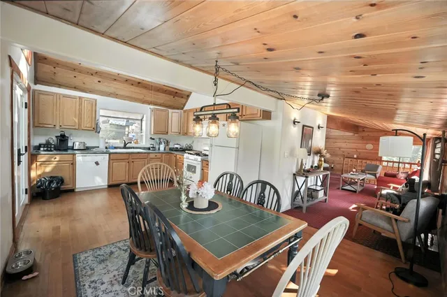 a view of a dining room and livingroom with furniture wooden floor a rug and a chandelier