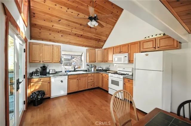 a kitchen with stainless steel appliances granite countertop a refrigerator a stove a sink dishwasher and white cabinets with wooden floor