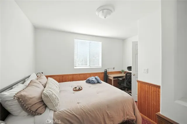 a bedroom with a bed and dresser with wooden floor