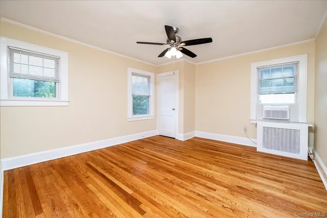 a view of empty room with wooden floor and fan