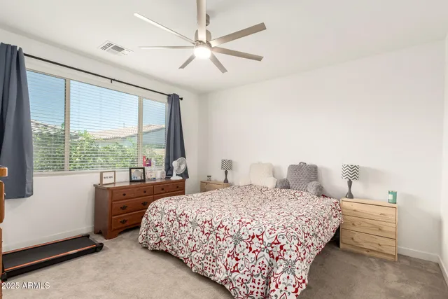 a bedroom with a large bed and a chandelier fan