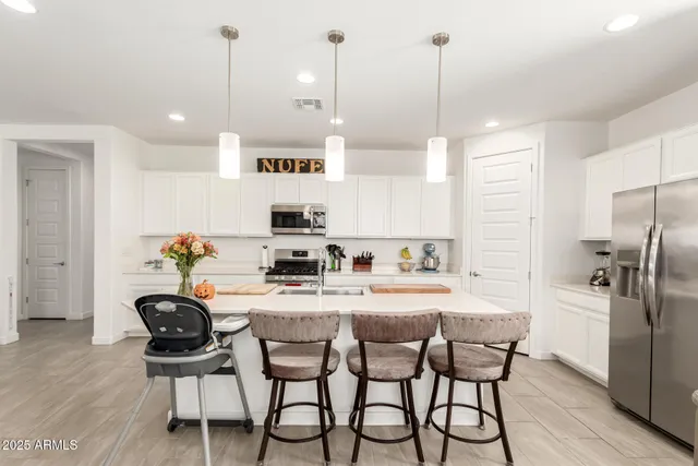 a kitchen with stainless steel appliances kitchen island granite countertop a dining table chairs and white cabinets