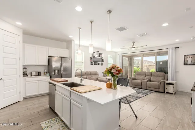 a kitchen with stainless steel appliances kitchen island granite countertop a sink a counter top space and living room view