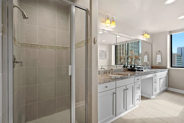 a bathroom with a granite countertop sink two mirror and a shower