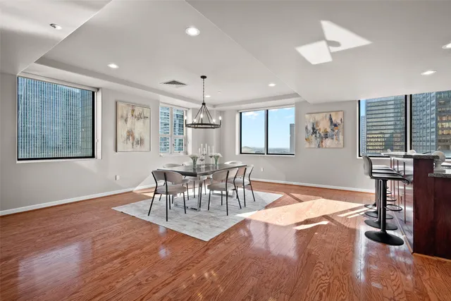 a dining room with wooden floor a chandelier a glass table and chairs