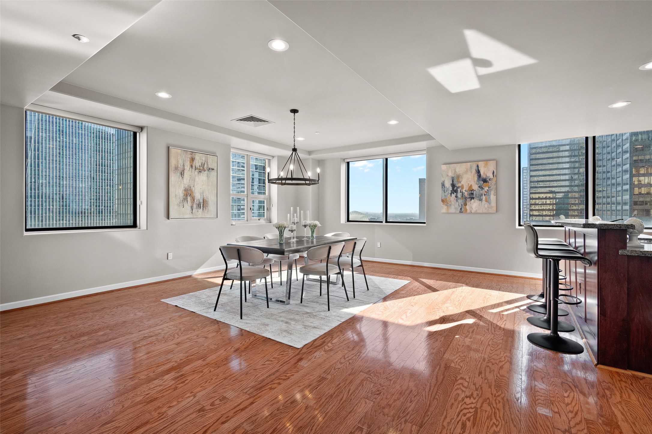 914 Main Street, Unit 1902 Houston, TX 77002 - Photo 4 of 32 a dining room with wooden floor a chandelier a glass table and chairs