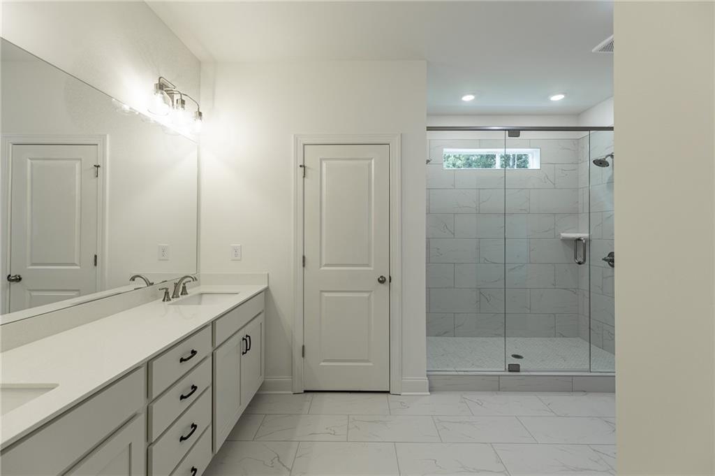 1210 Austin Road Winder, GA 30680 - Photo 38 of 56 a spacious bathroom with a shower sink vanity and mirror