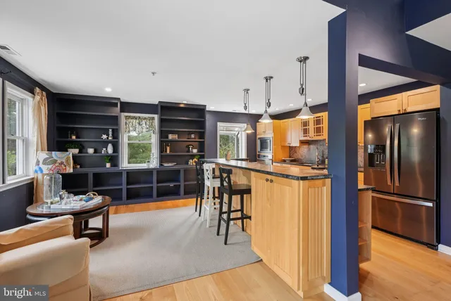 a kitchen with stainless steel appliances kitchen island granite countertop a refrigerator a stove and a wooden cabinets