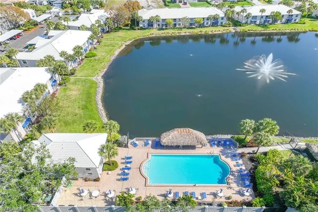 an aerial view of a house with a lake boats and trees all around
