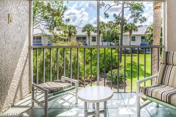 a view of a patio with couches plants and large trees