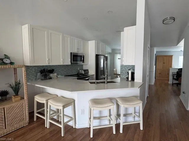 a kitchen with stainless steel appliances granite countertop a table chairs refrigerator a sink and dishwasher