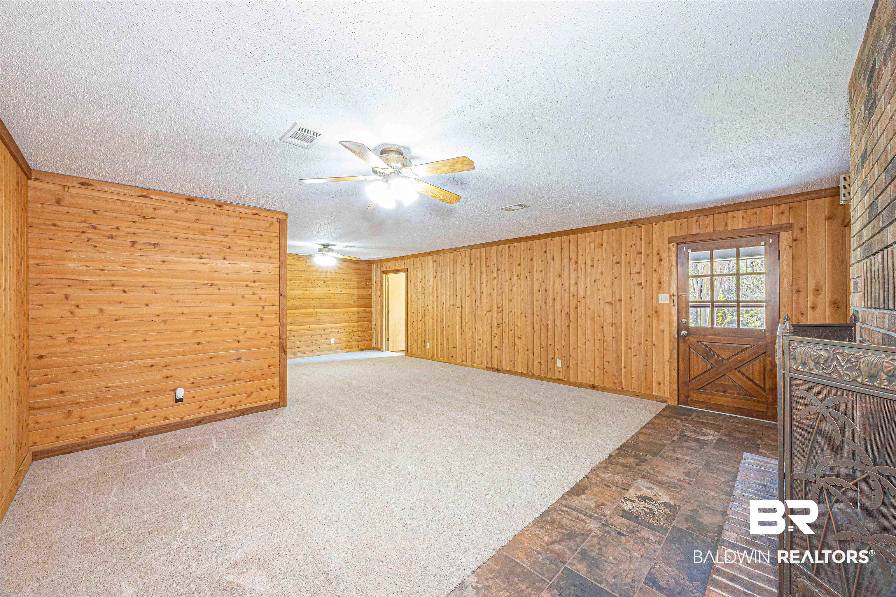 43101 Brown Road Bay Minette, AL 36507 - Photo 24 of 81 Unfurnished living room with wooden walls, stone finish flooring, a textured ceiling, ceiling fan, and carpet