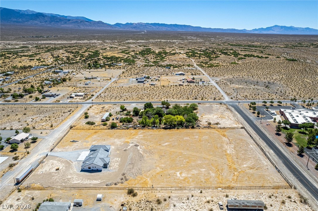 5910 East Kellogg Road Pahrump, NV 89061 - Photo 55 of 58 A vast, level lot awaits, surrounded by arid landscape and distant mountain ranges, offering serene desert living.