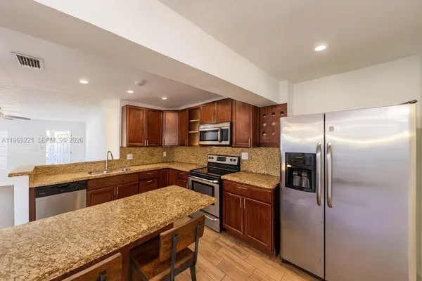a kitchen with granite countertop stainless steel appliances cabinets a sink and a center island