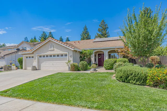 a view of a white house with a big yard and potted plants