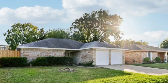 a view of a white house next to a yard and large trees
