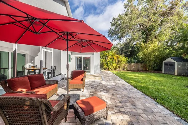 a patio with tables and chairs under an umbrella