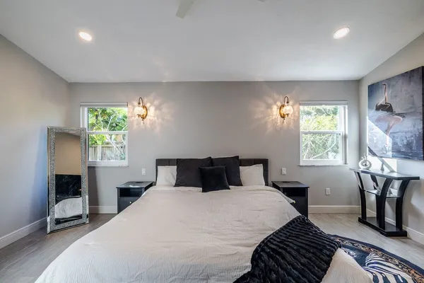 a bedroom with a bed table chair and window