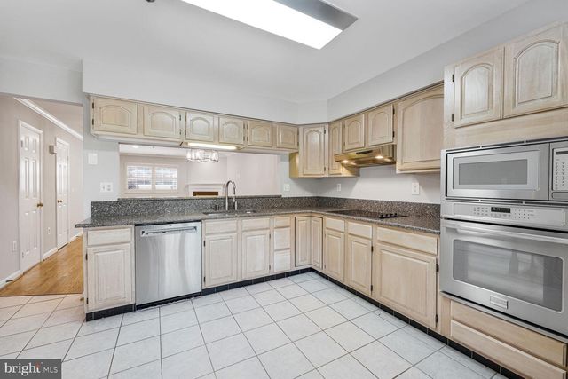 a kitchen with granite countertop white cabinets stainless steel appliances and a sink