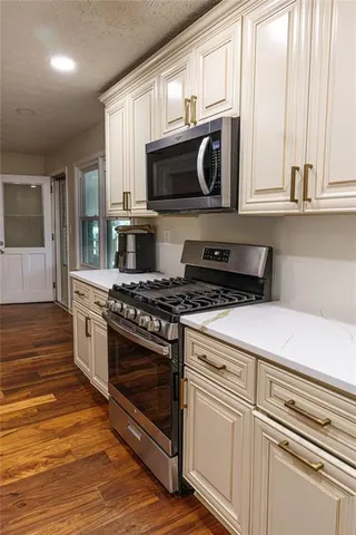 a kitchen with stainless steel appliances granite countertop a stove a microwave and a white cabinets