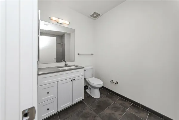 a bathroom with a granite countertop toilet a sink and a mirror