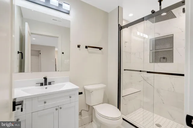 a bathroom with a toilet a sink a mirror and shower