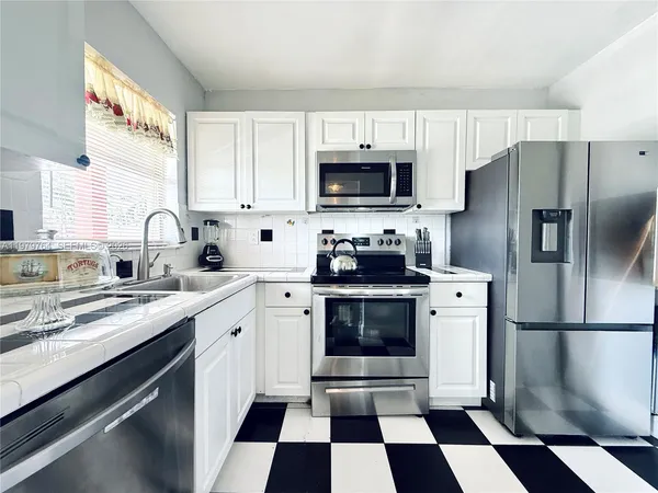a kitchen with stainless steel appliances a stove a sink and a microwave