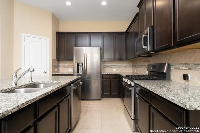 a kitchen with kitchen island granite countertop wooden cabinets and a stove top oven