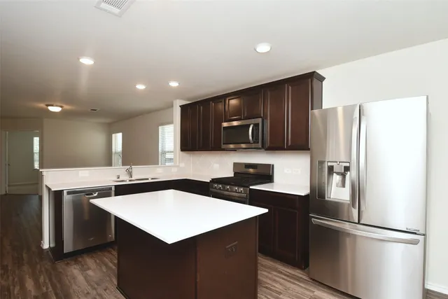 a kitchen with kitchen island a sink refrigerator and microwave