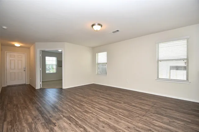 an empty room with wooden floor and windows