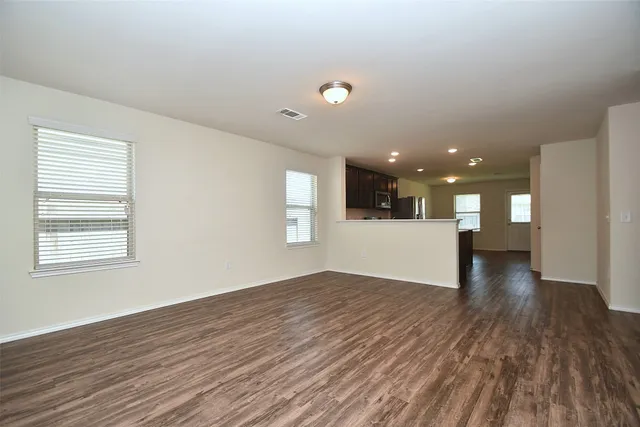 a view of empty room with wooden floor and windows