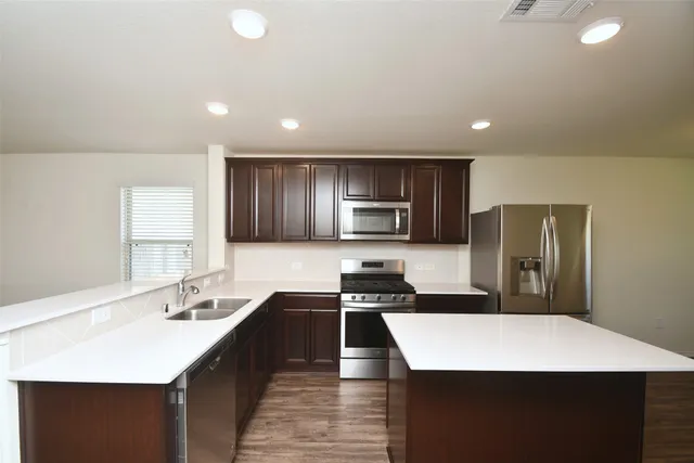 a kitchen with stainless steel appliances a sink a stove a refrigerator a center island and a refrigerator