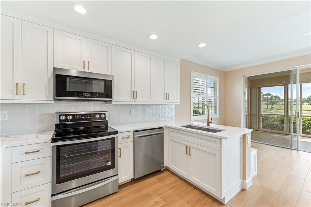 23151 Rosedale Drive, Unit 101 Estero, FL 34135 - Photo 19 of 20 Another view of the kitchen with new cabinets, countertops, sink, ceramic backsplach, and ceramic wood-look floor tile